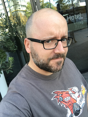 Photograph of Patrick H. Lauke, standing outside of a hotel in Berlin, wearing a Mozilla t-shirt.
